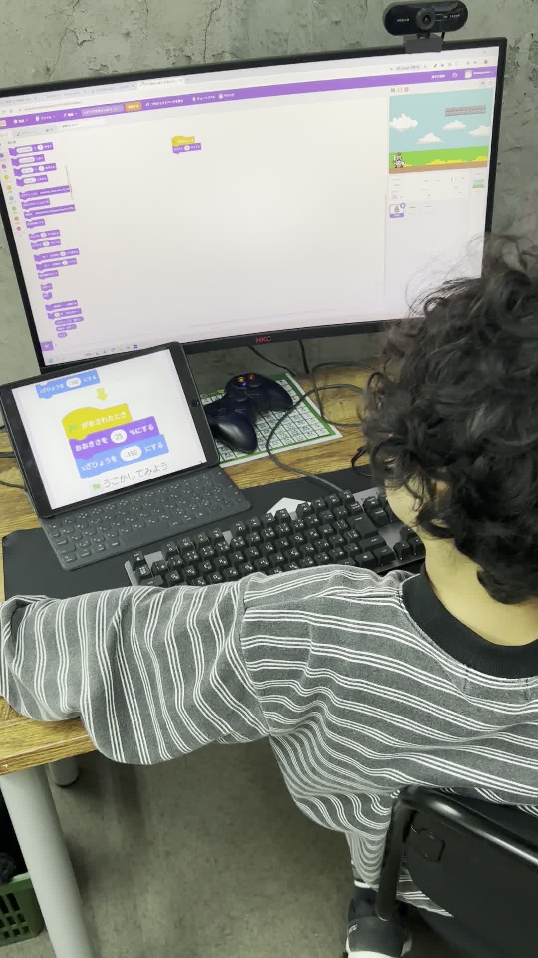 プログラム画面とタブレットを見ながら操作する後ろ姿