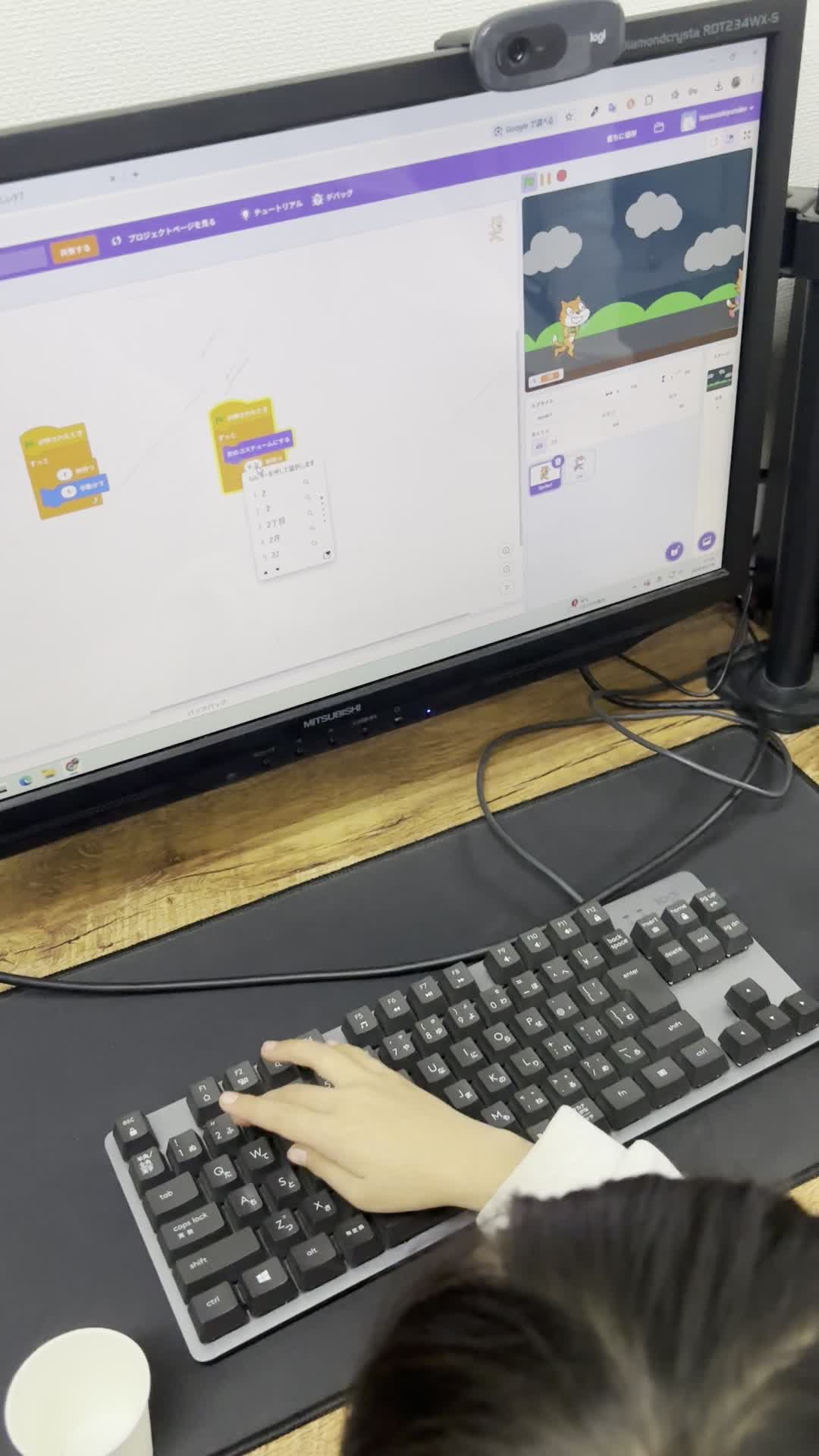 プログラム画面を見ながらキーボードを操作する手元
