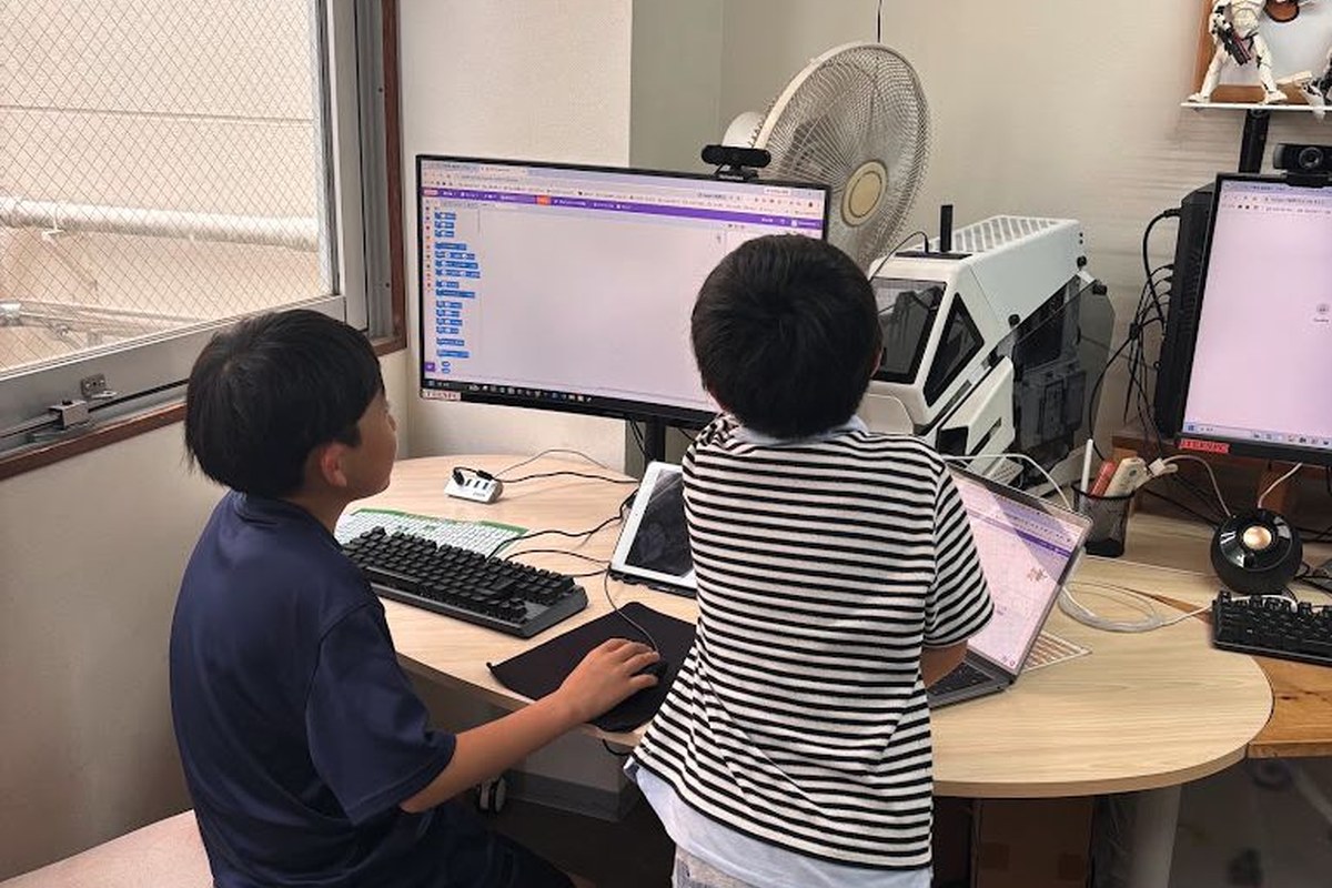 パソコン画面を見ながらプログラミングに取り組む子どもの後ろ姿
