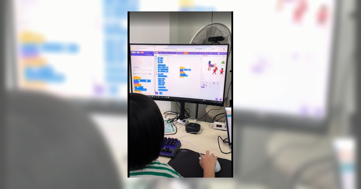 小学生がパソコン画面を見ながらプログラミング学習に集中する様子