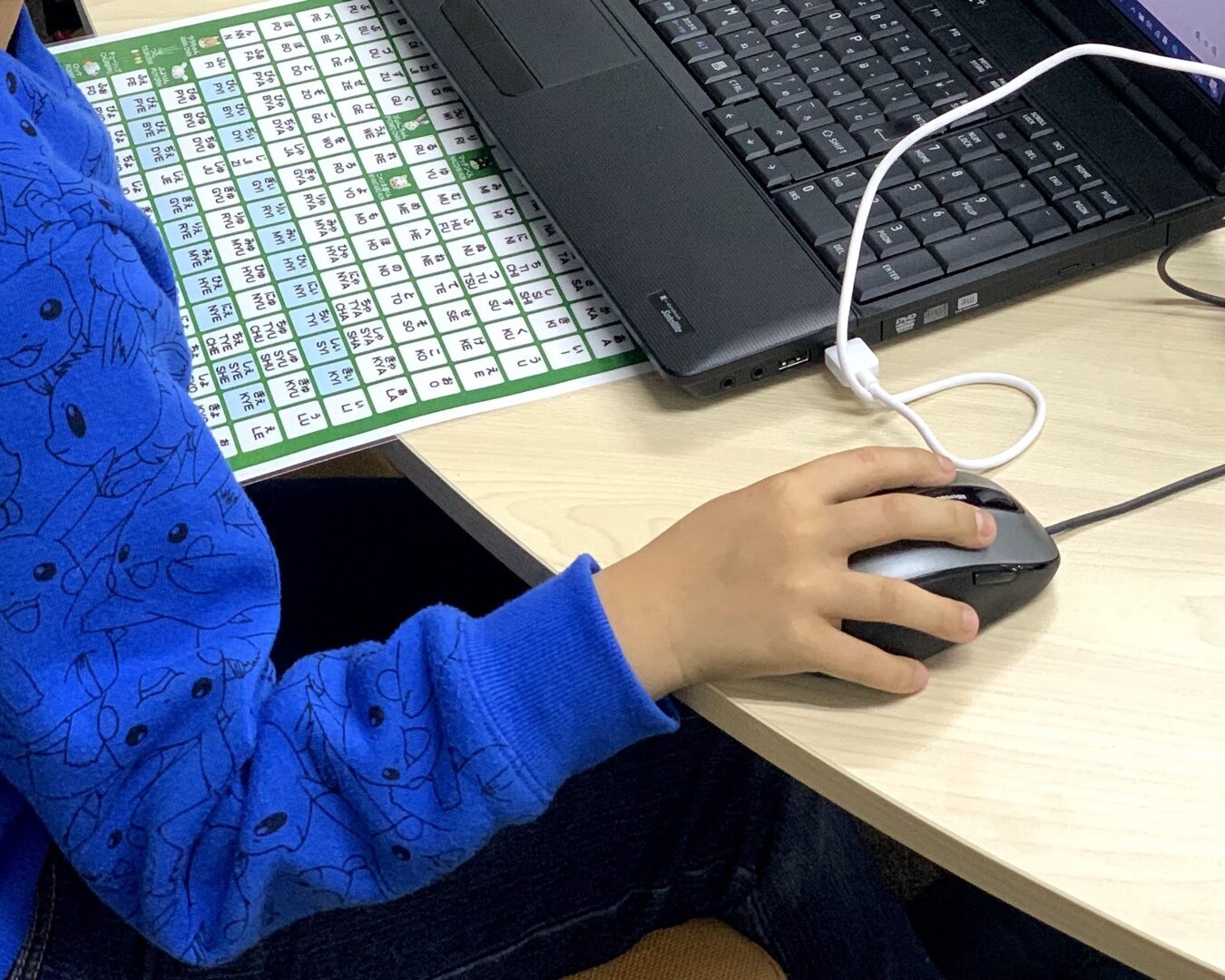 Scratchの画面を見ながら、子どもがキーボードとマウスで作品を操作している手元